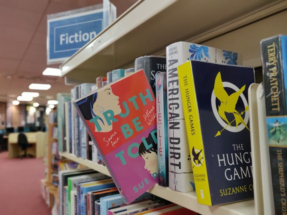 A selection of books on a shelf with one slightly pulled out.